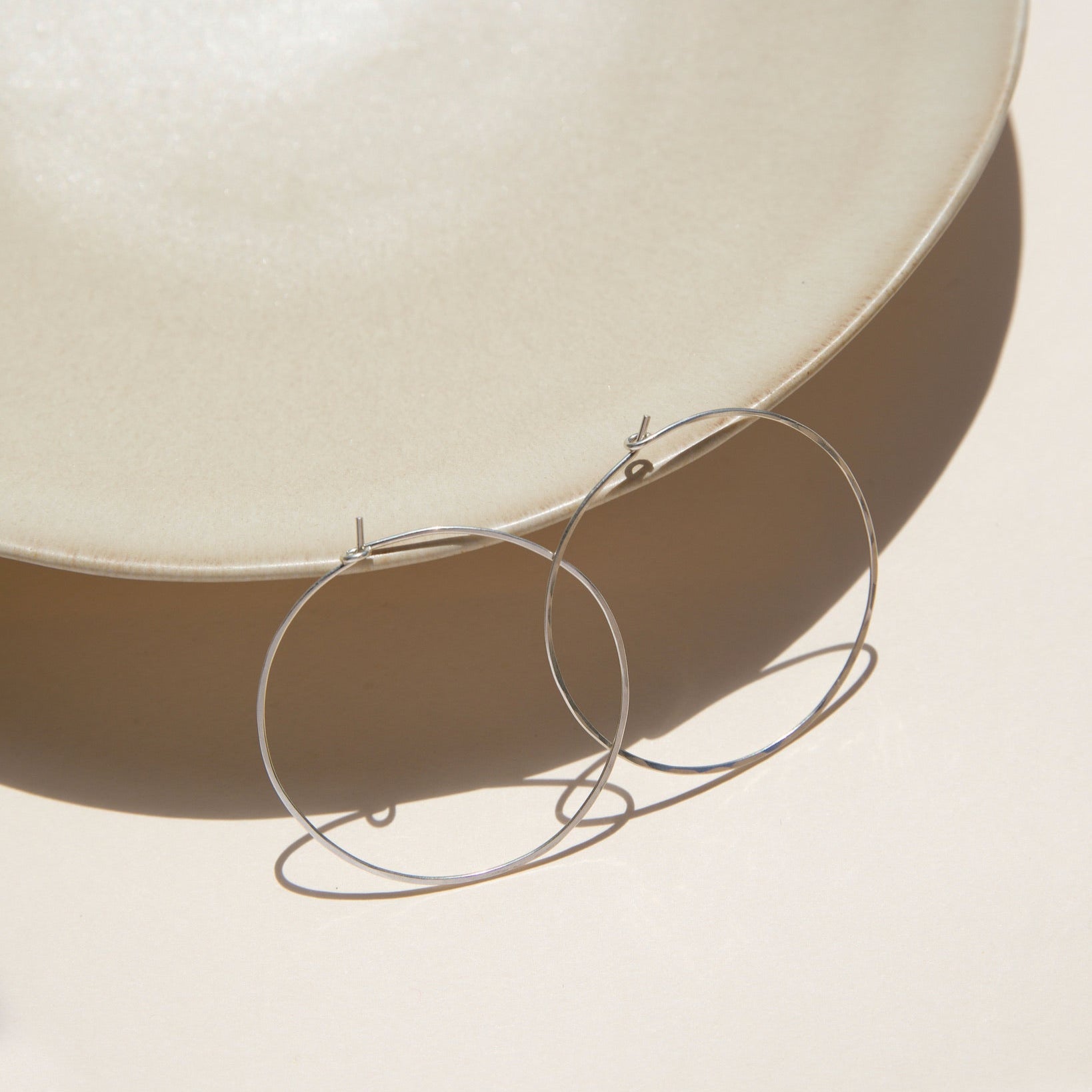 sterling silver hammered hoop earrings on a light dish