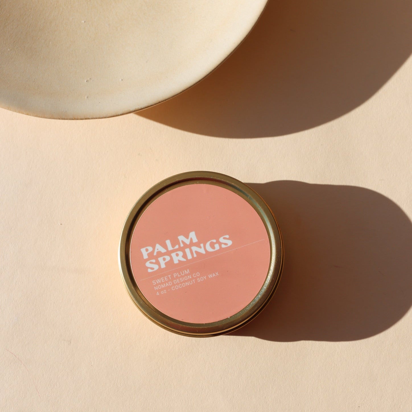 peach colored candle tin in the sunlight - scent is Palm Springs