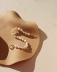 Gold toggle bracelet featuring a strand of lustrous freshwater pearls and a bold circular toggle clasp.
