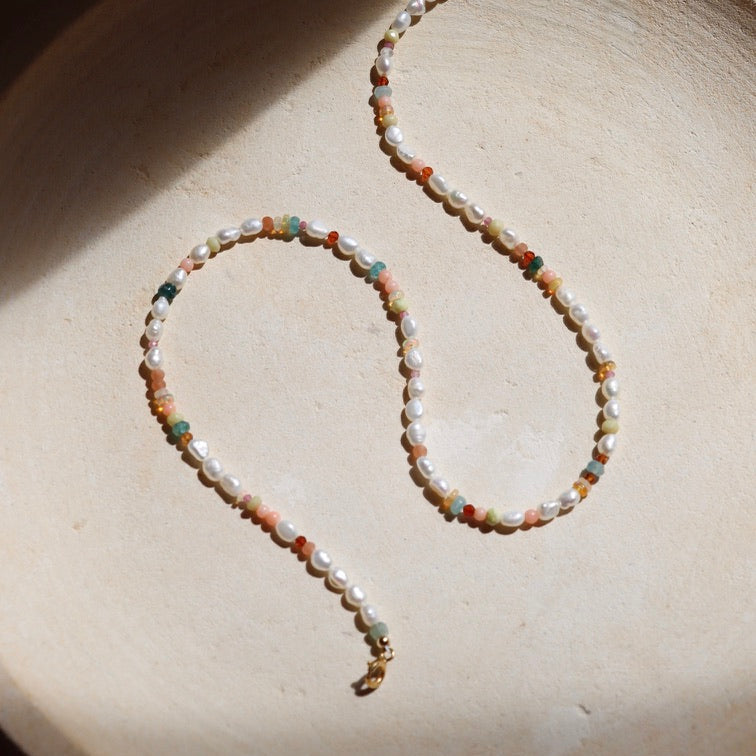 pearl and gemstone beaded necklace with 14k gold fill clasps on a light dish
