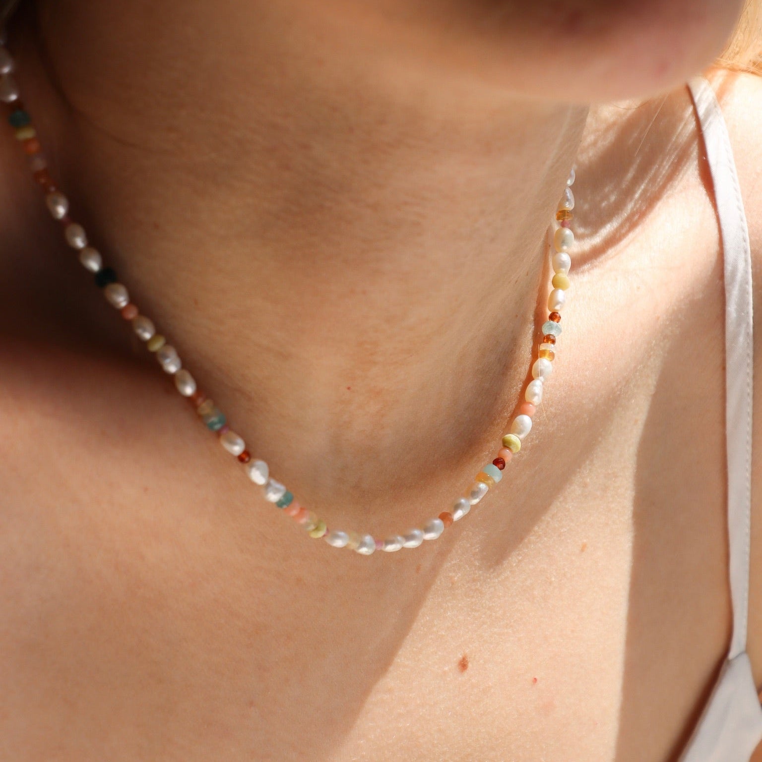 model wearing gemstone and pearl beaded necklace 