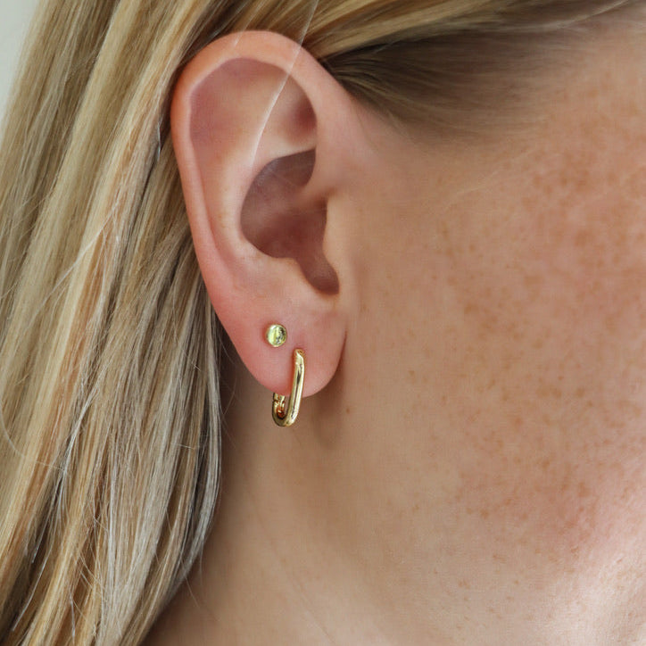 model wearing 14k gold fill huggie hoops with round peridot studs