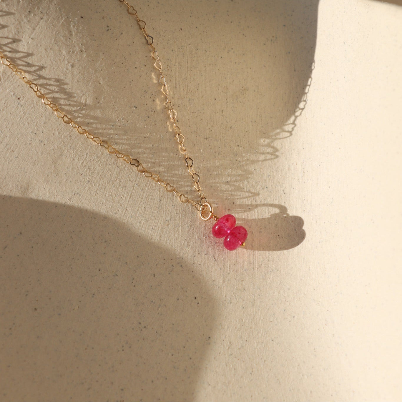 pink topaz charm in 14k gold fill on petite heart chain - light background with shadows