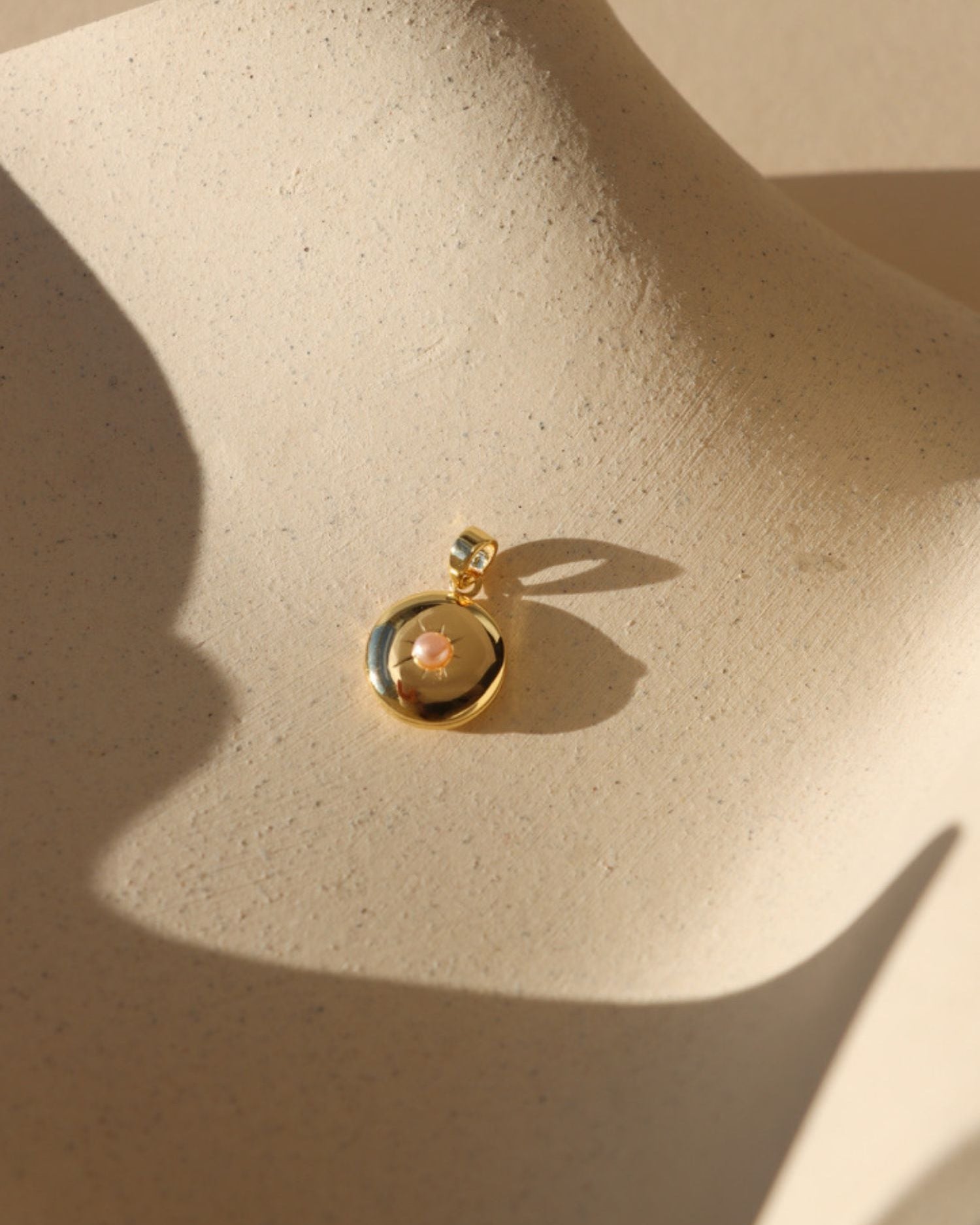 Pink Pearl Locket on tan dish in sunlight