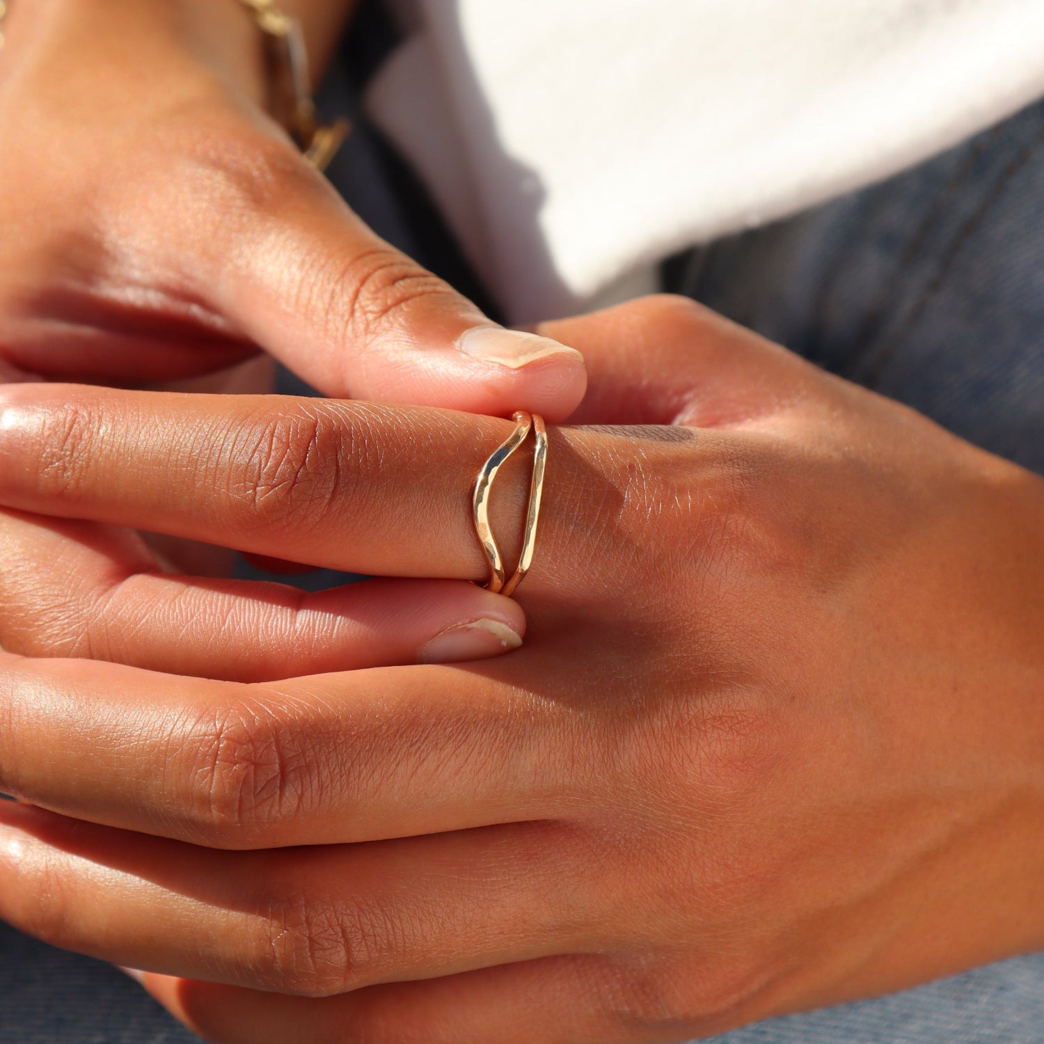 Model wearing two 14k gold fill minimalist rings stacked together, featuring an open plunge-shaped ring paired with a hammered band ring, styled on the hand in warm natural sunlight