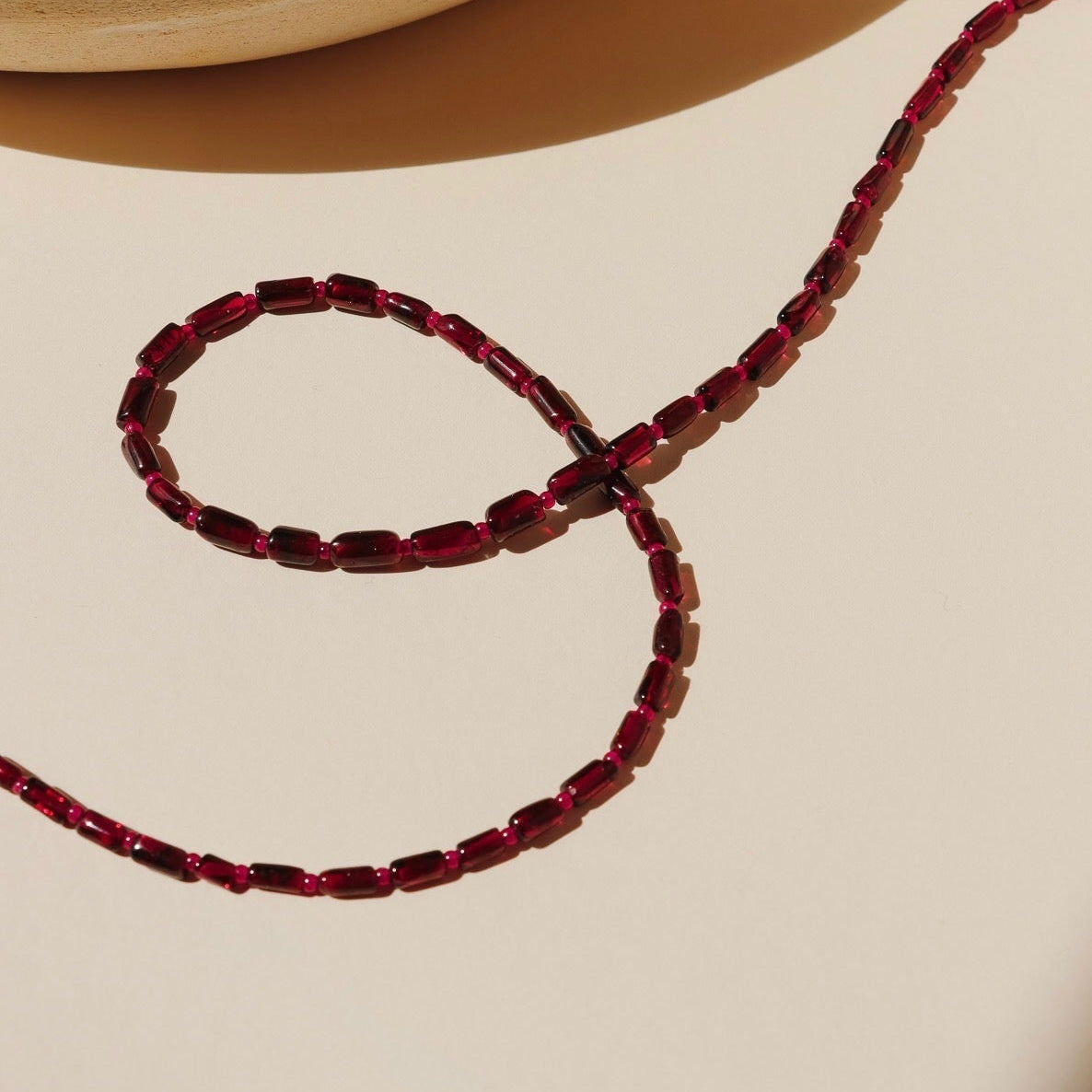 garnet and ruby beaded necklace on a light surface
