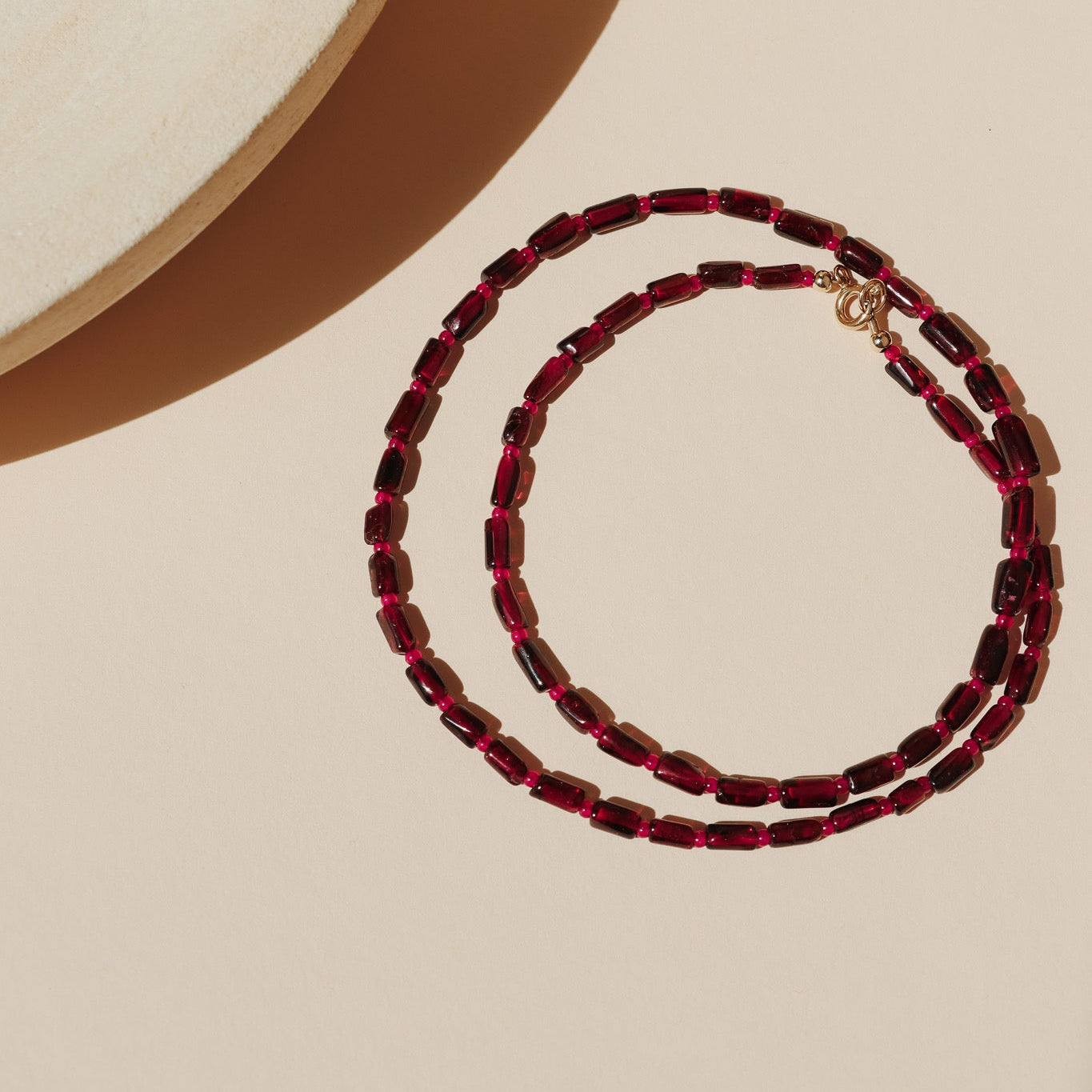 garnet and ruby beaded necklace on a light surface