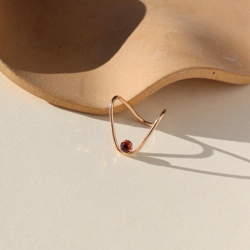 Our Rising Tide Ring features a 4mm red garnet set in 14k gold fill, designed in the shape of a wave. The gemstone rests at the base of the wave. 