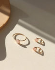 Our rose quartz Huggies feature a 5mm rose quartz gemstone. These earrings are made to hug your ear featuring a curved 14k gold fill post that will wrap around your ear. The earrings are on a white backdrop. 