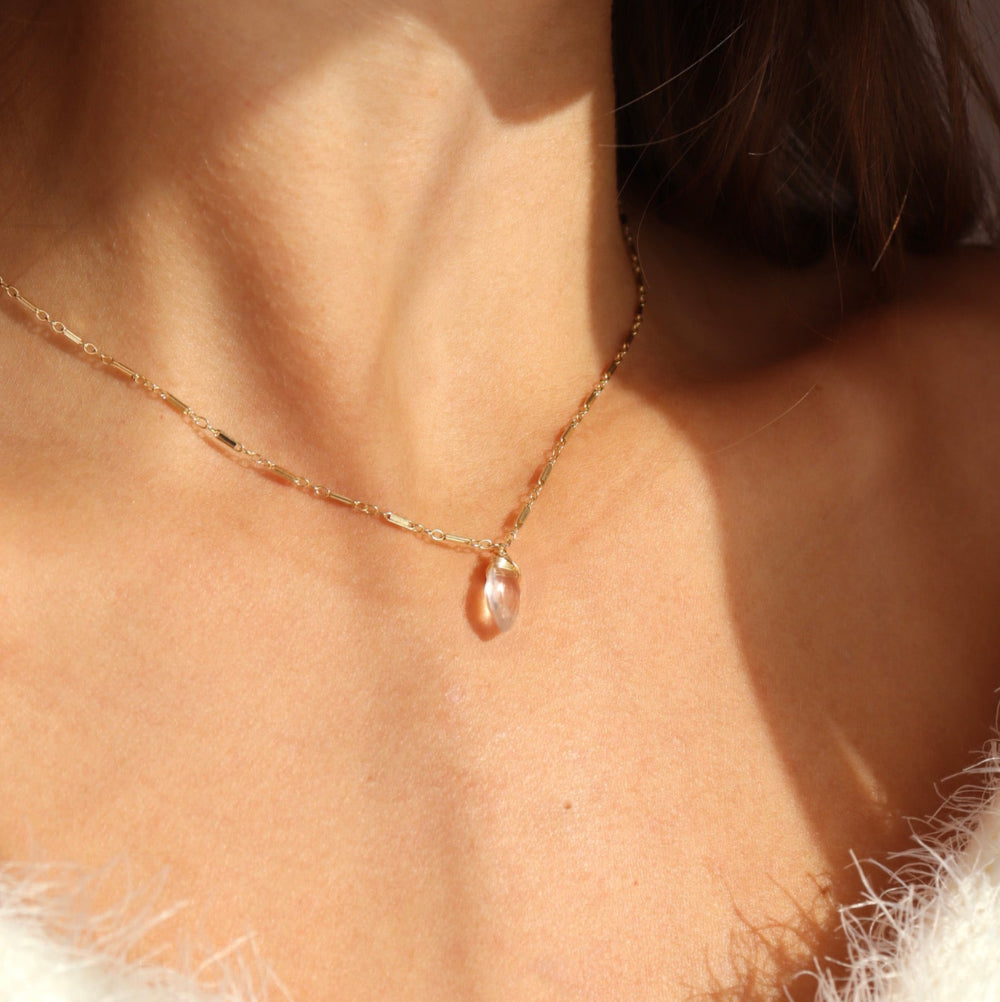 Model wearing 14k gold fill Marisol bar +link Chain featuring a wire-wrapped rose quartz gemstone. 