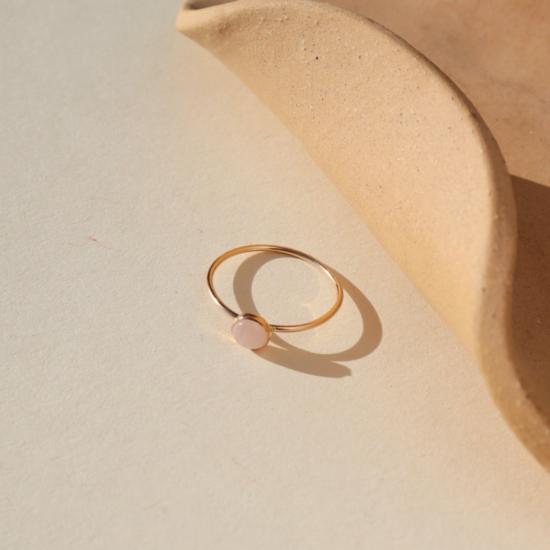 14k gold fill ring featuring a 5mm rose quartz gemstone set in a 14k gold fill thin band. The ring is displayed on a cream backdrop. 