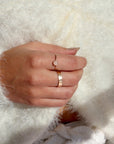 Model wearing a 14k gold fill ring featuring a 5mm rose quartz gemstone set in a 14k gold fill thin band. Model is wearing a white fuzzy jacket. 