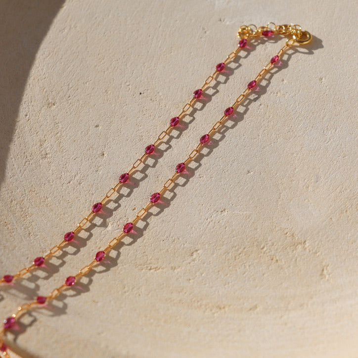 14k gold fill chain with ruby transparent gemstones on a light dish