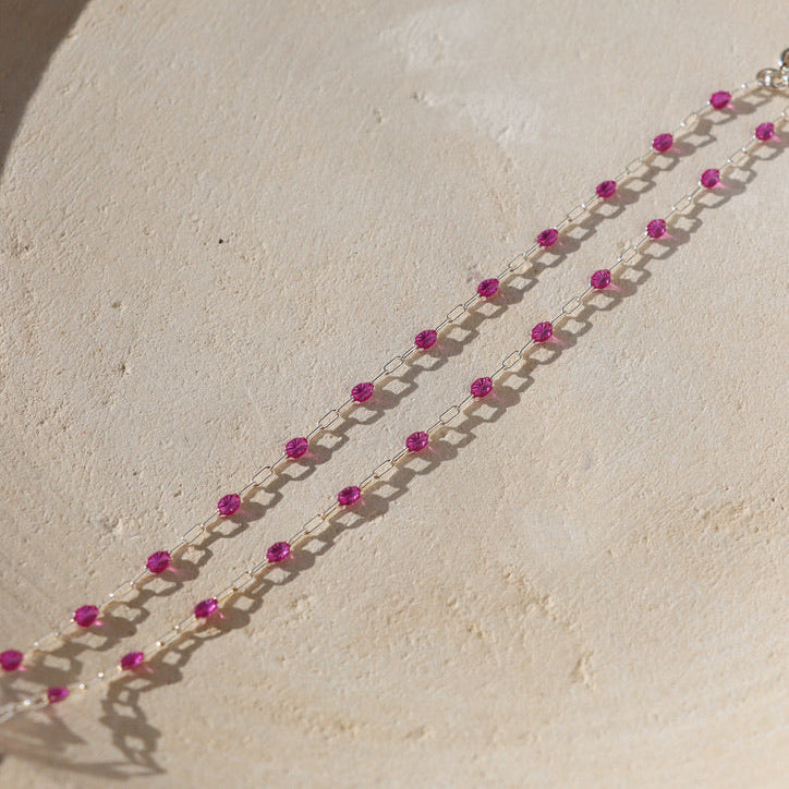 sterling silver chain bracelet with ruby gemstones on a light dish 