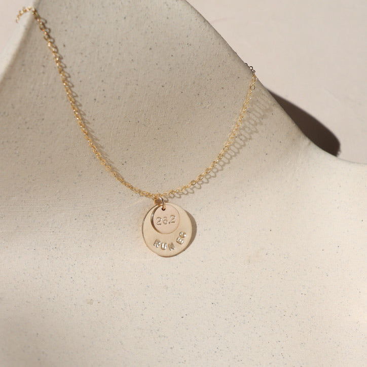 14k gold fill hand stamped round disc charms on a delicate chain necklace on a light surface