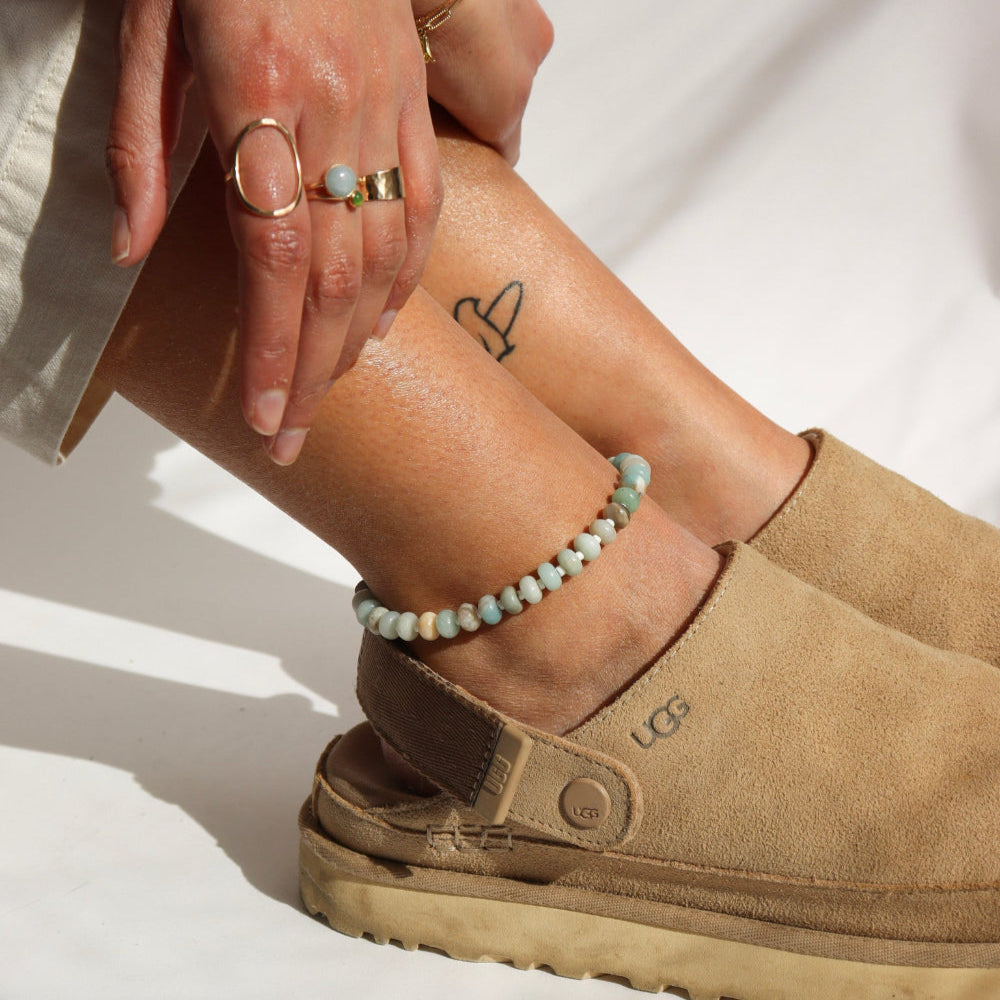 Model wearing a fully beaded 14k gold fill anklet filled with amazonite gemstones and shell spacer beads. 