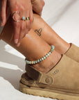 Model wearing a fully beaded 14k gold fill anklet filled with amazonite gemstones and shell spacer beads. 