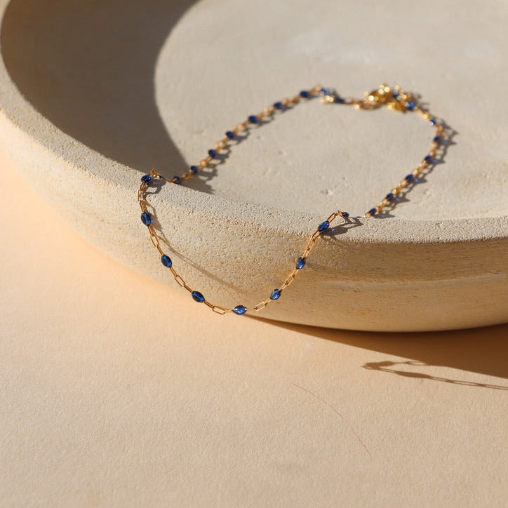 14k gold fill chain with sapphire gemstones on a light dish
