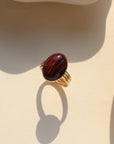 The Scarlett Ring, available in 14k gold fill or sterling silver, features a stunning Red Tiger Eye gemstone on a triple 14k gold fill band