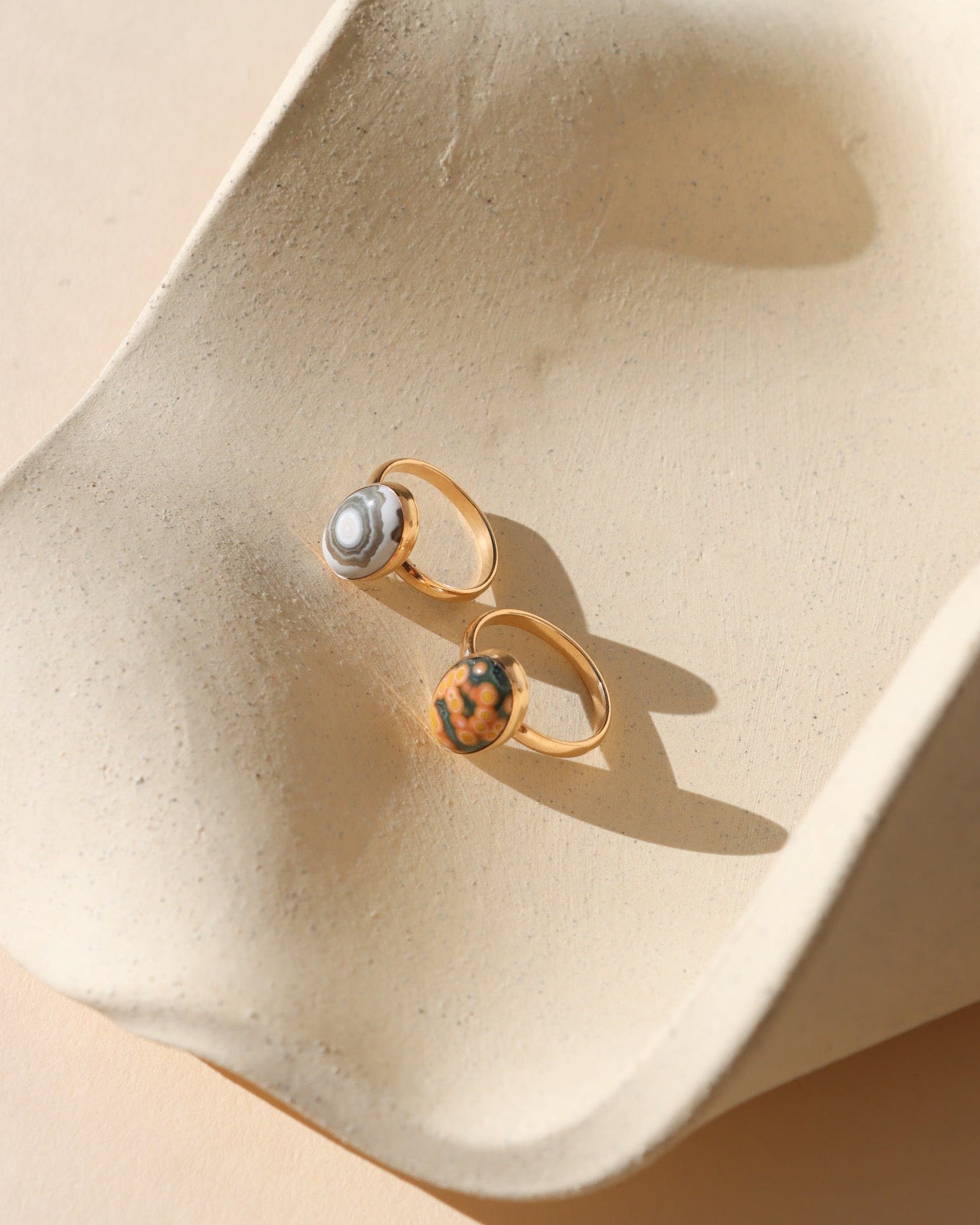 14k gold fill rings with oval ocean jasper stones on a light dish