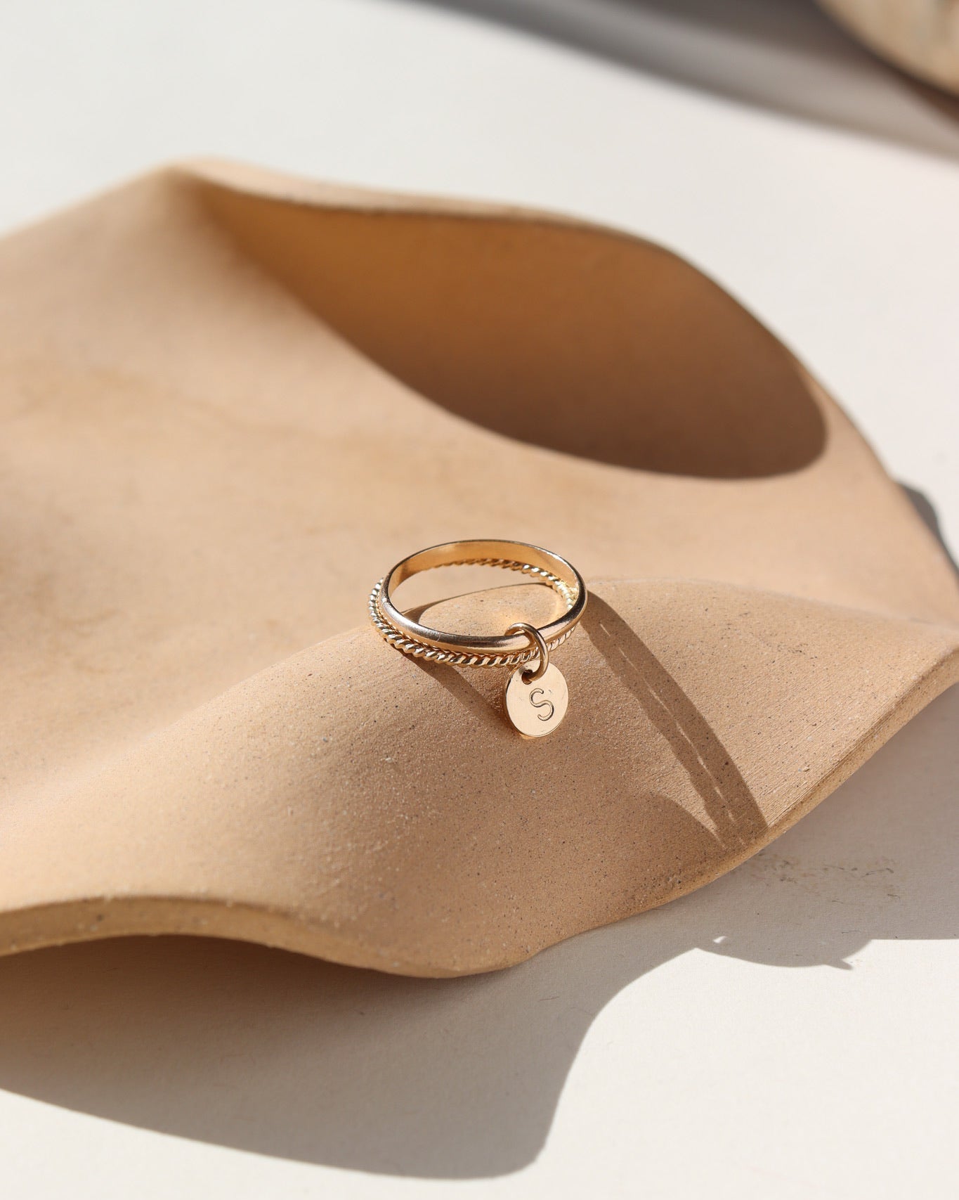 A smooth band stacked with a spiral 14k gold fill band, with a small "S" stamped disc attached to both rings. 