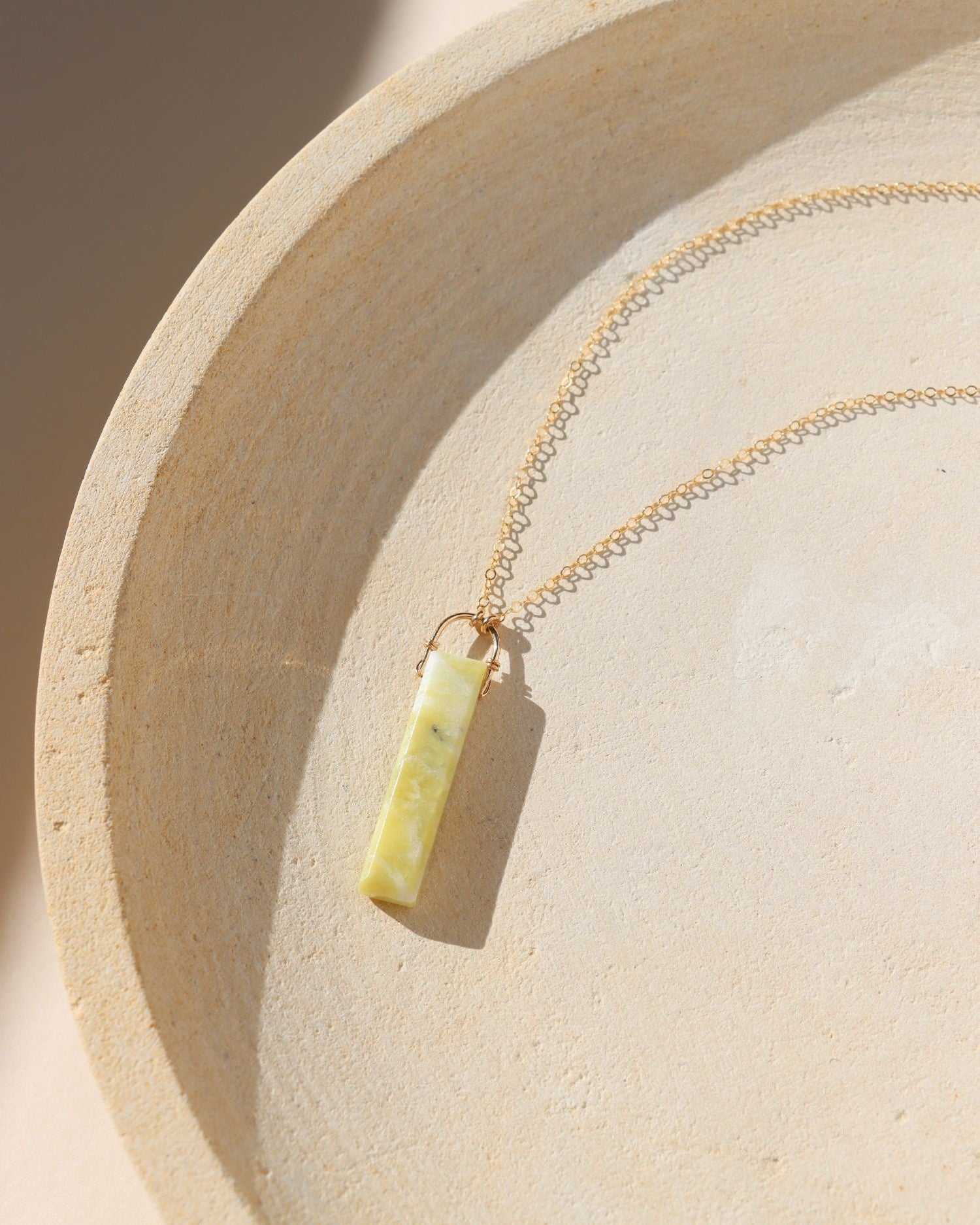 delicate 14k gold fill chain necklace with teardrop hackmanite pendant on a light dish