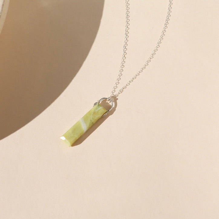 sterling silver chain necklace with rectangle serpentine pendant on a light dish