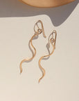 14k gold filled sidewinder earrings laying on a sunlit white dish.