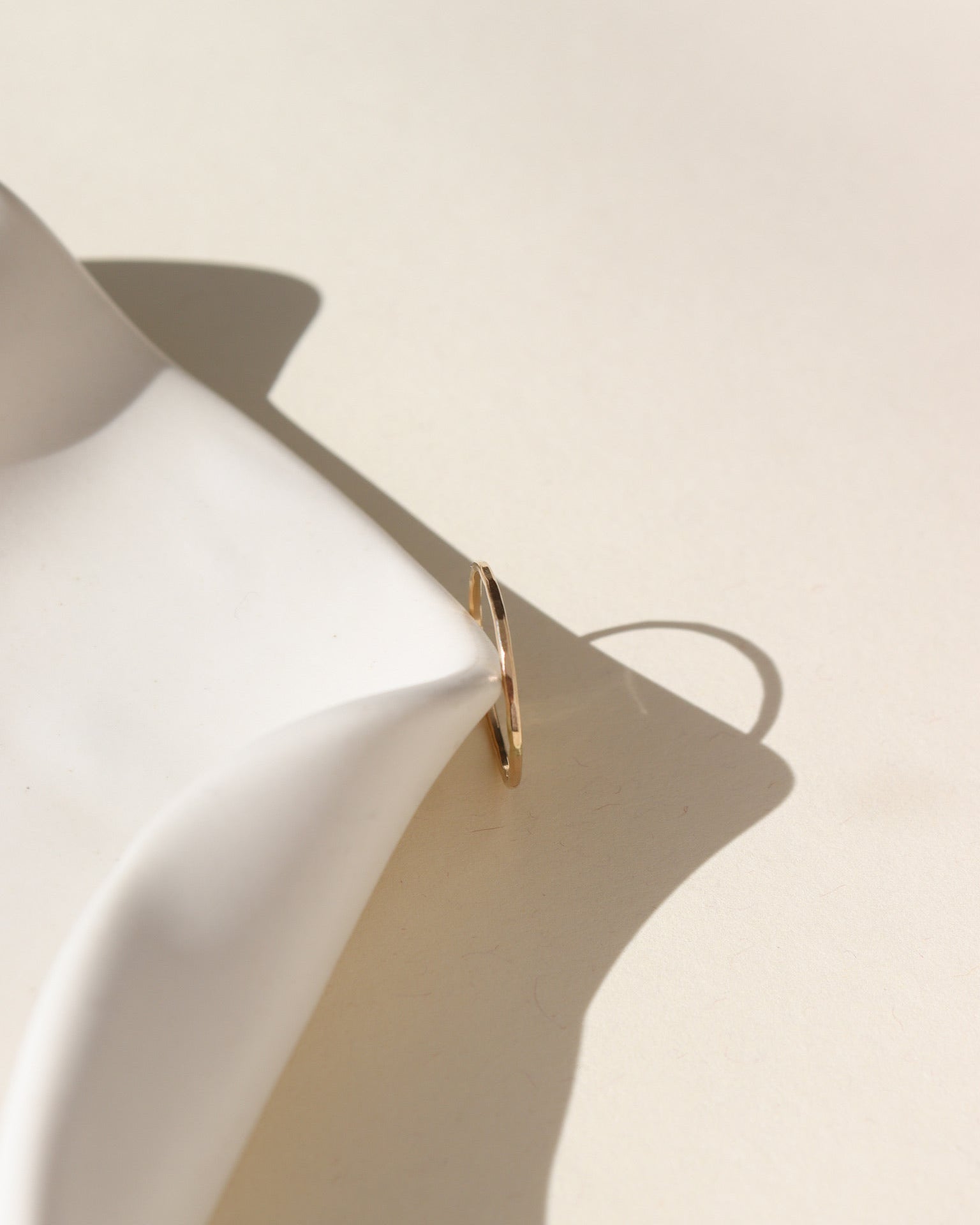 lightly hammered simple band in 14k solid gold  by a white dish in the sun