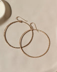 14k gold fill Soleil Hoops laid on a white paper in the sunlight