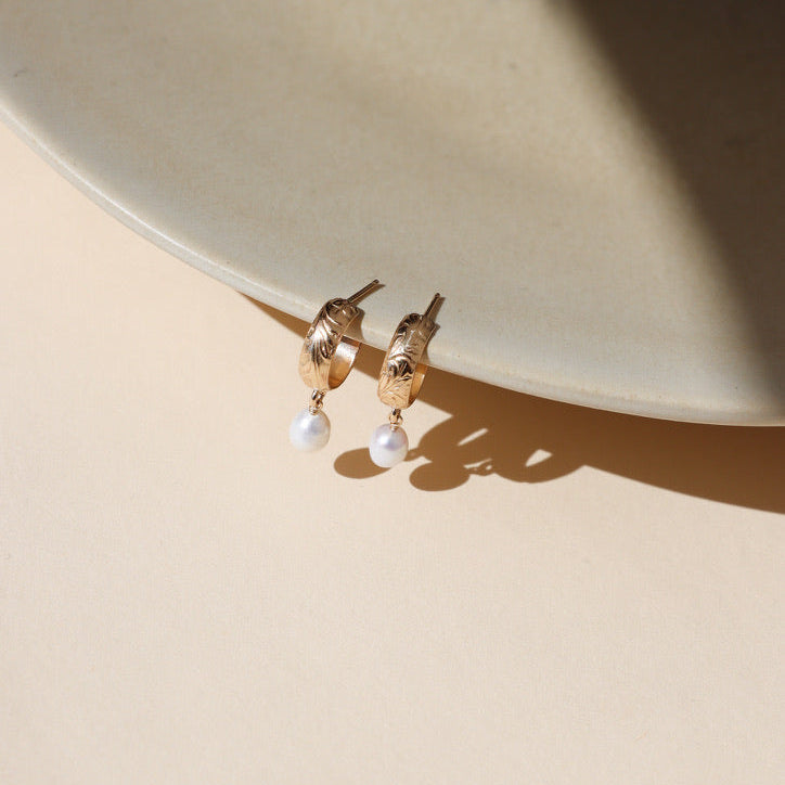 14k gold fill floral hoop studs with edison pearls dangling on a light dish