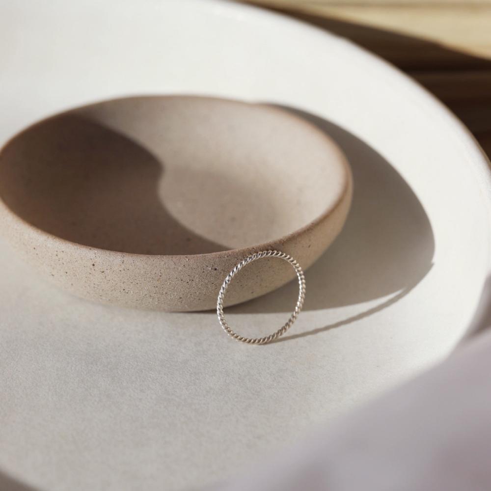 Simple spiral silver band, displayed on a white dish. 