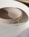 Simple spiral silver band, displayed on a white dish. 