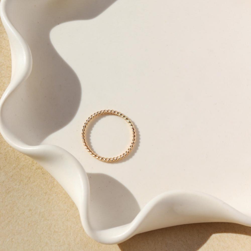 Simple spiral gold band, displayed on a white dish. 