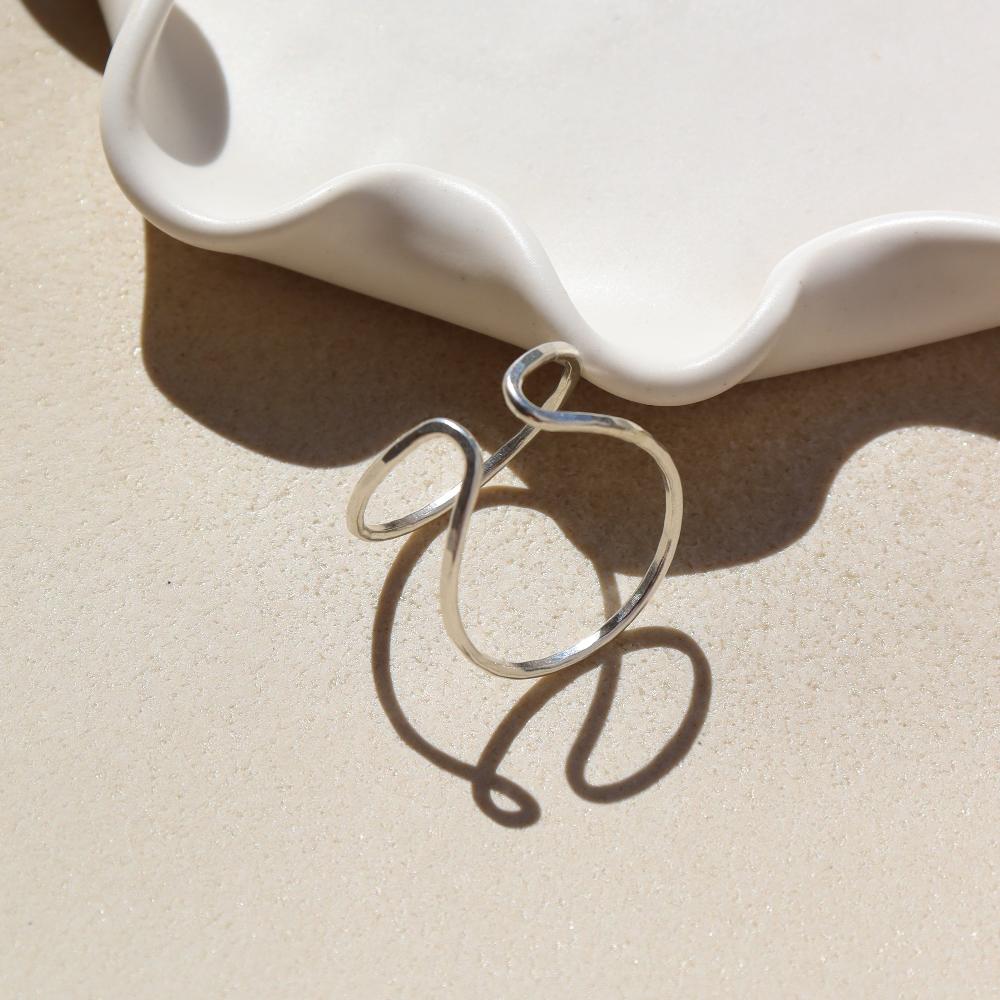 Sterling silver Sundari Cuff laid in the sun on a white plate