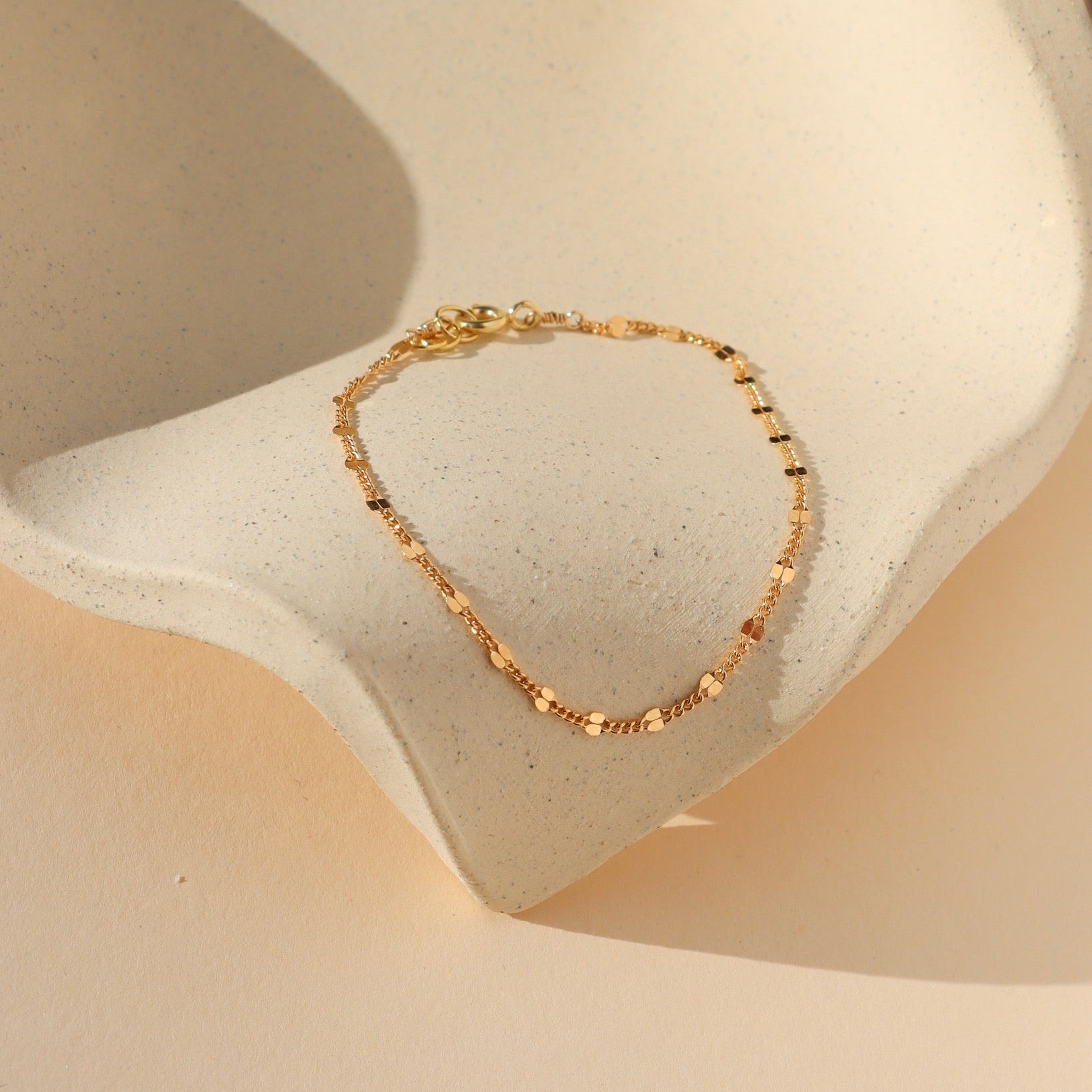 Gold sunburst chain bracelet with delicate textured links that catch the light.