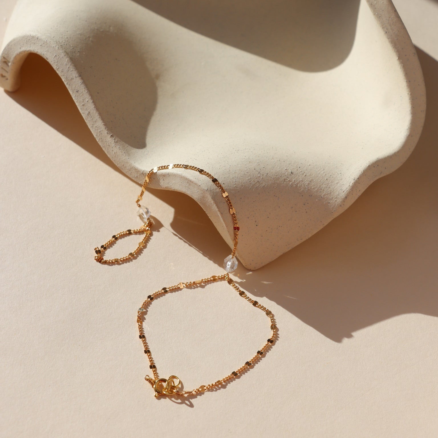 Gold sunburst hand chain featuring delicate textured links and a raw Herkimer diamond accent.