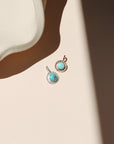 14k gold fill and sterling silver charms with round turquoise stones in the sunlight