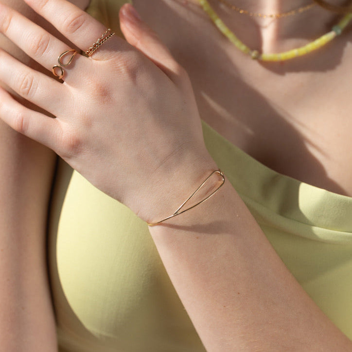 model wearing 14k gold fill wire bracelet in the sunlight