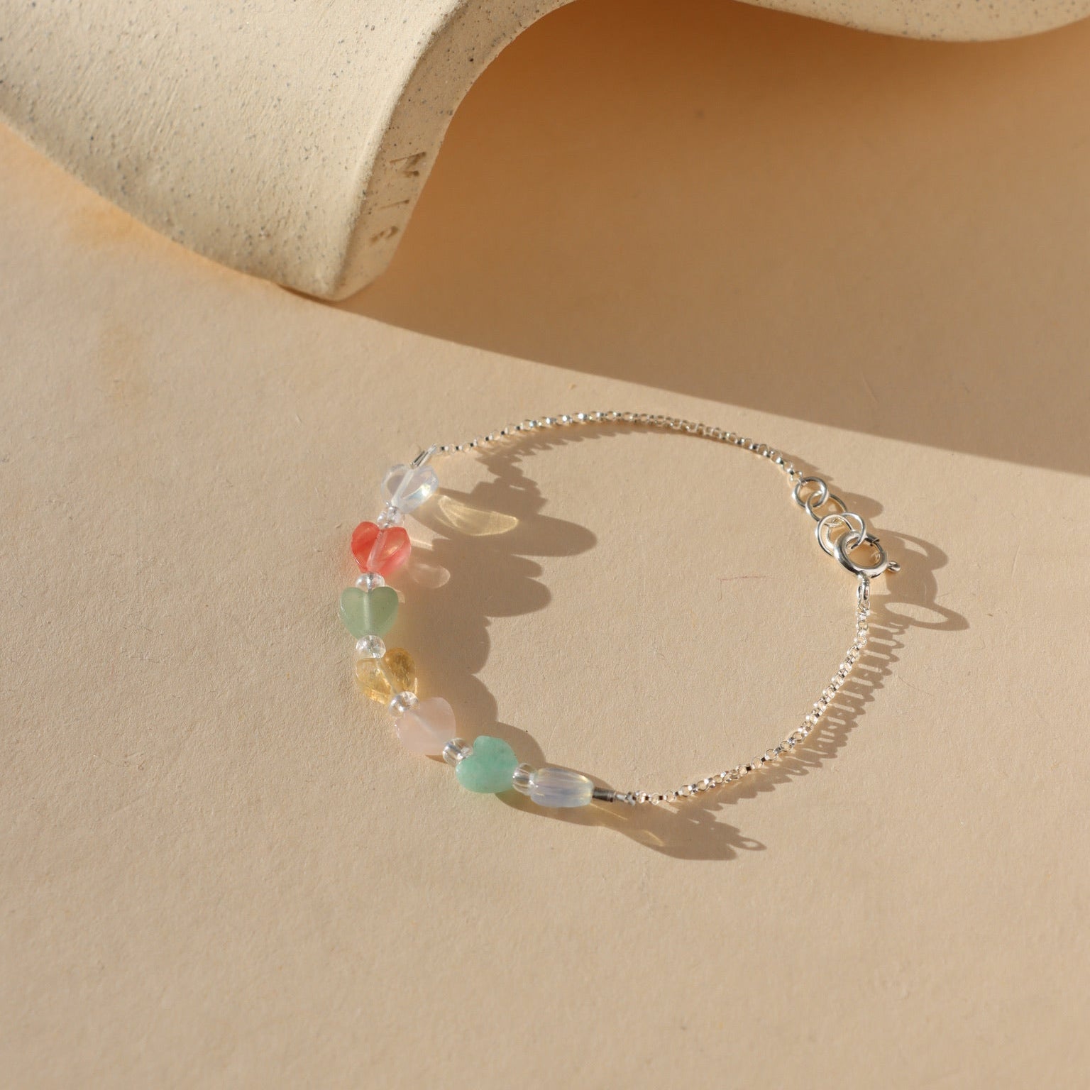 multicolored heart beads with sterling silver chain laid on light background in the sunlight