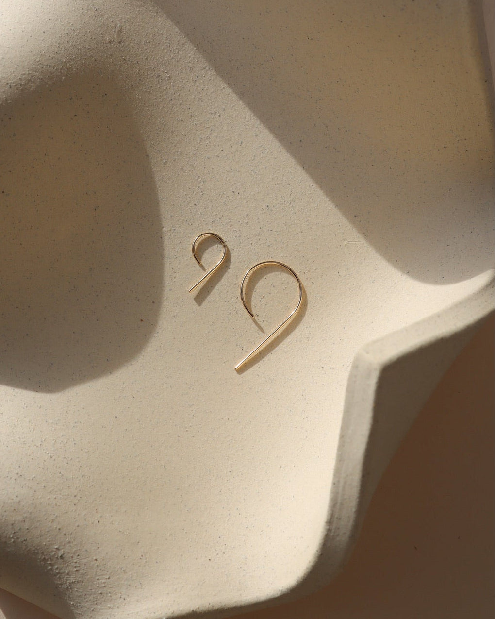 14k gold fill 9 shaped earrings in 2 sizes on a light dish
