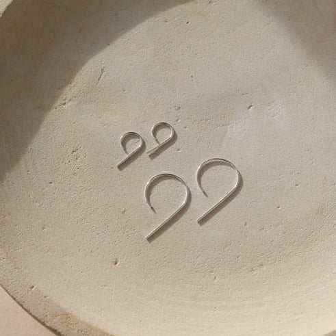 sterling silver nine shaped earrings in two sizes on a light dish