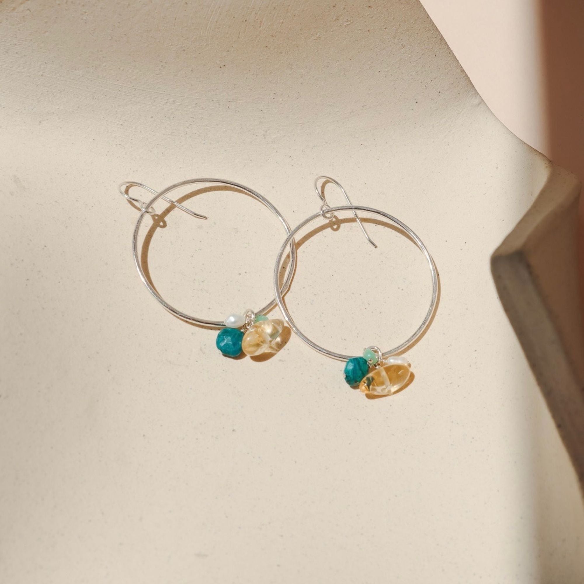 sterling silver round hoops with gemstone drops on a light dish