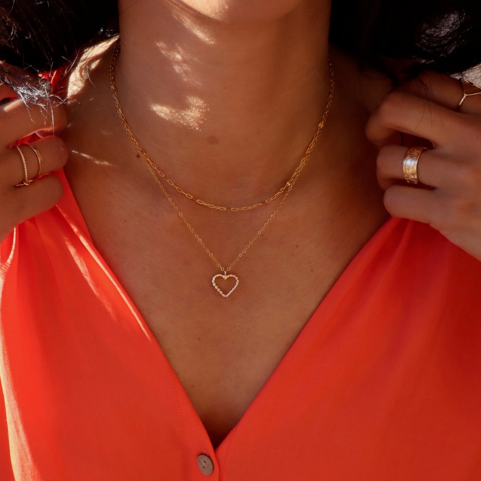 model wearing spiral wire heart shaped pendent necklace in 14k gold fill layered with 14k gold fill chain necklace