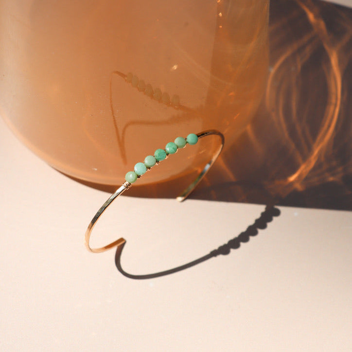  14k gold fill jewelry including a cuff with wire wrapped chrysoprase stones in the sunlight