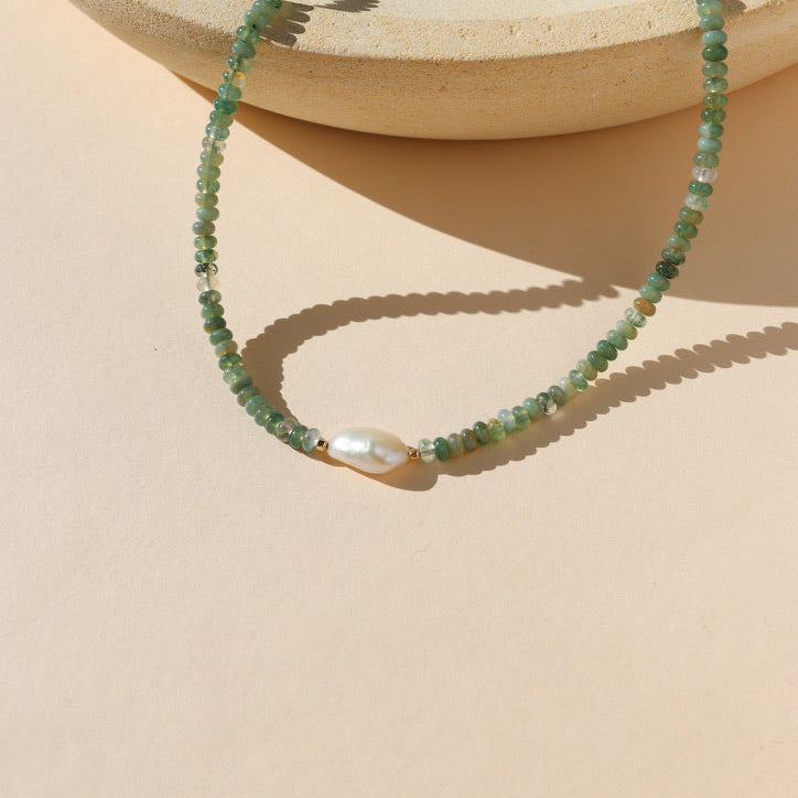 beaded necklace featuring moss agate and pearl beads on a light background