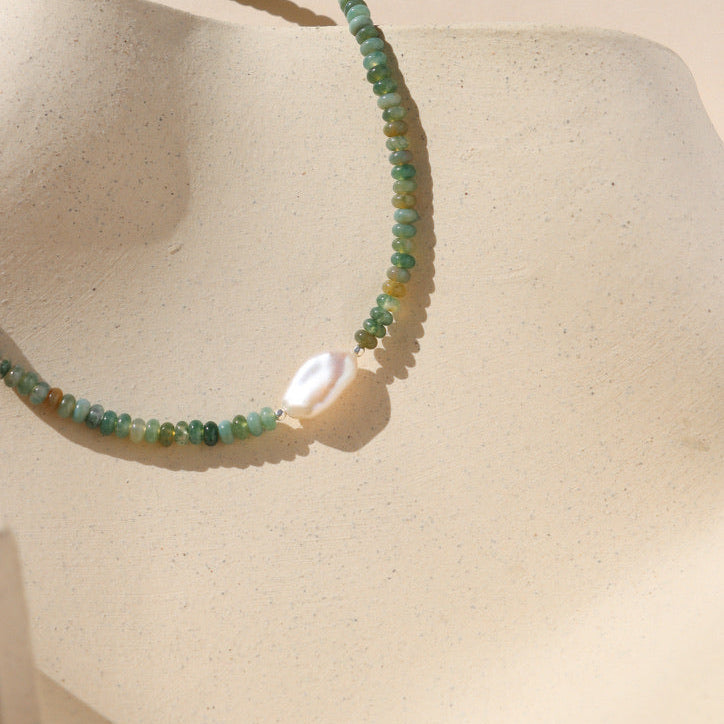 beaded necklace featuring moss agate and pearl beads on a light background