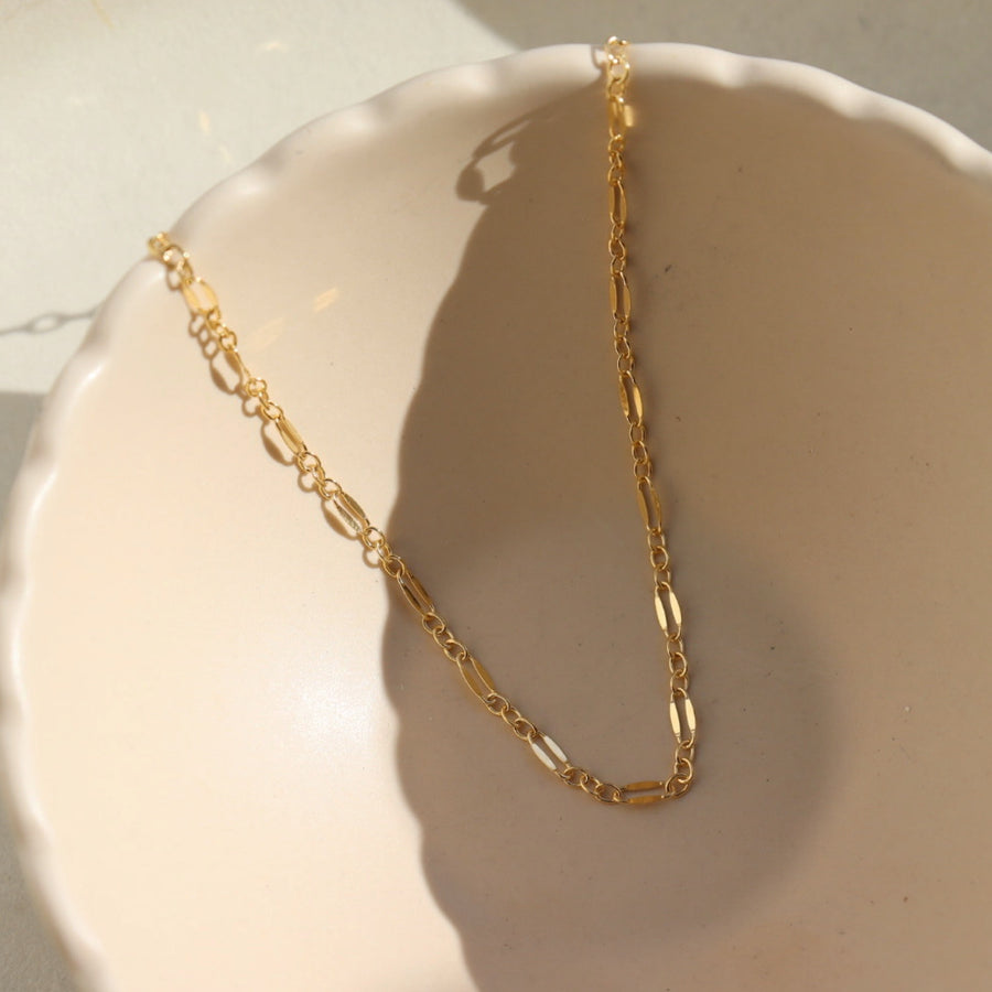 14k gold fill Sylvie choker laid on a tan plate in the sunlight. 