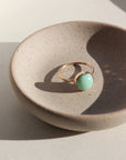 14k gold fill Lucky Ring placed on a gray plate in the sunlight. This Ring features the Chrysoprase gemstone.