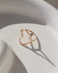 a hammered open heart shaped ring, photographed on a ceramic dish